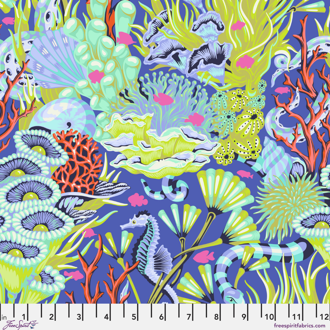 Fabric swatch with a lush underwater print filled with coral, sea plants, shells, seahorses, and other ocean details on a rich marine blue background with a ruler at the bottom.